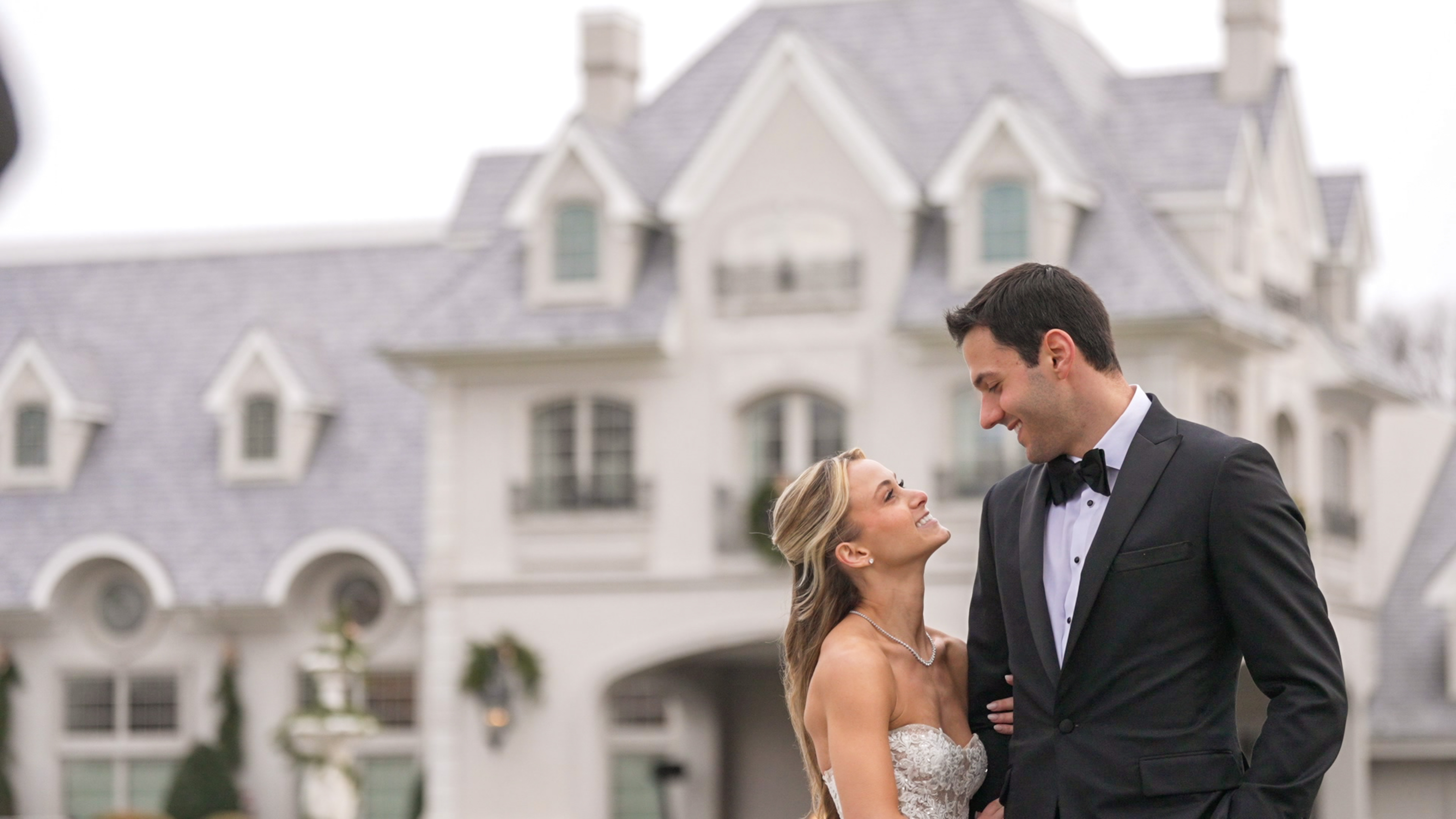 Bride and Groom looking at each other outside with a chateau in the background.