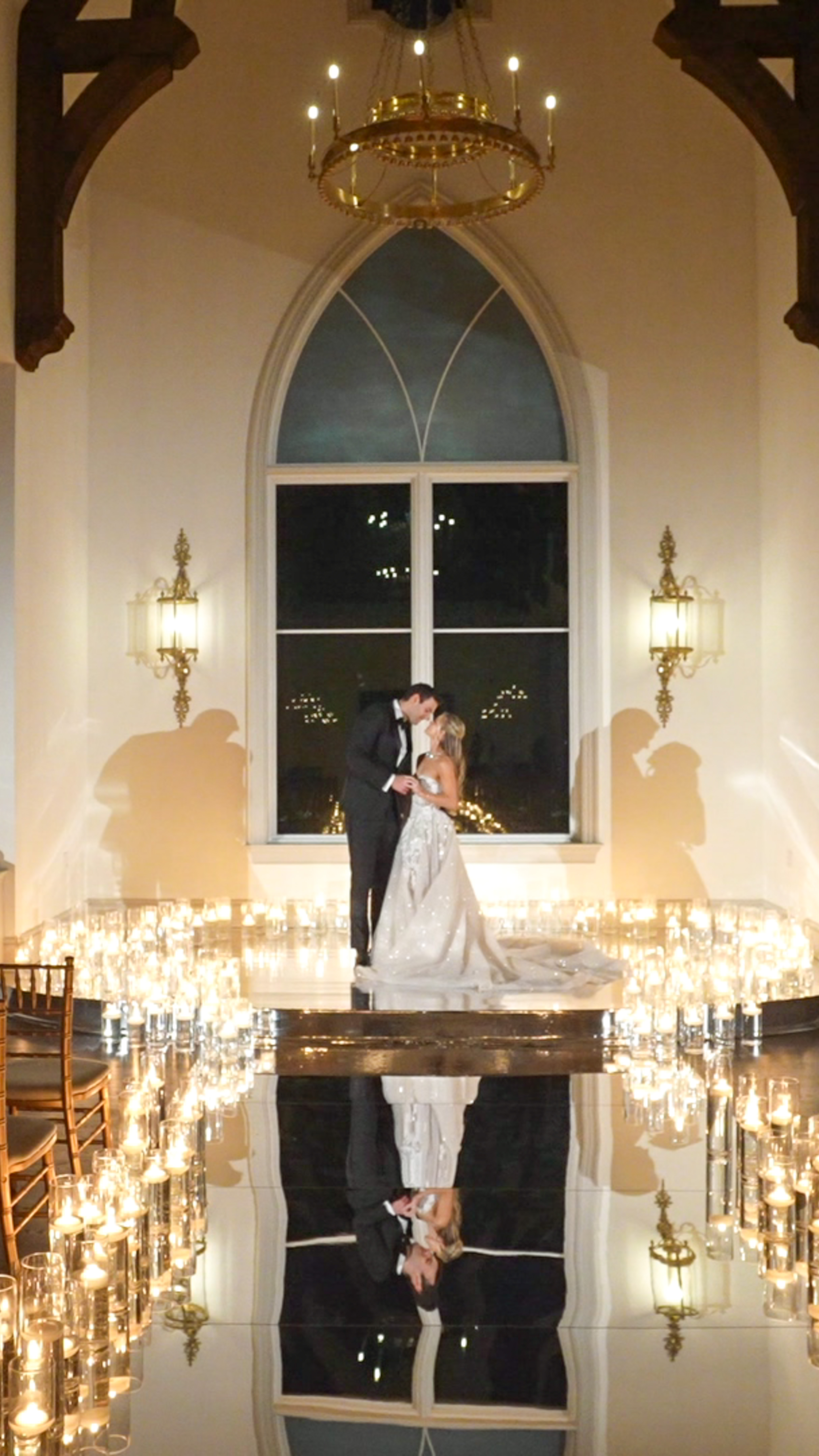 A bride and groom kissing with candles surrounding them at an alter in a small church.